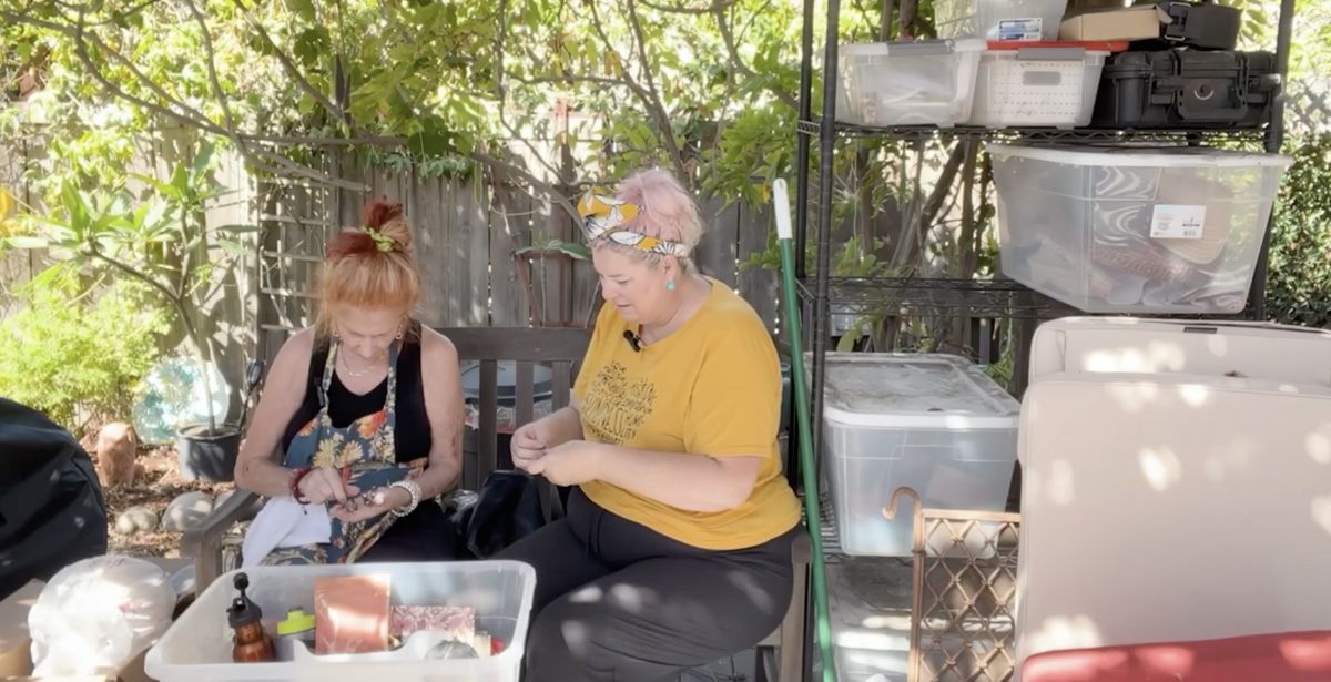 Unison and Doriot sorting through a bin of belongings on a garden bench.