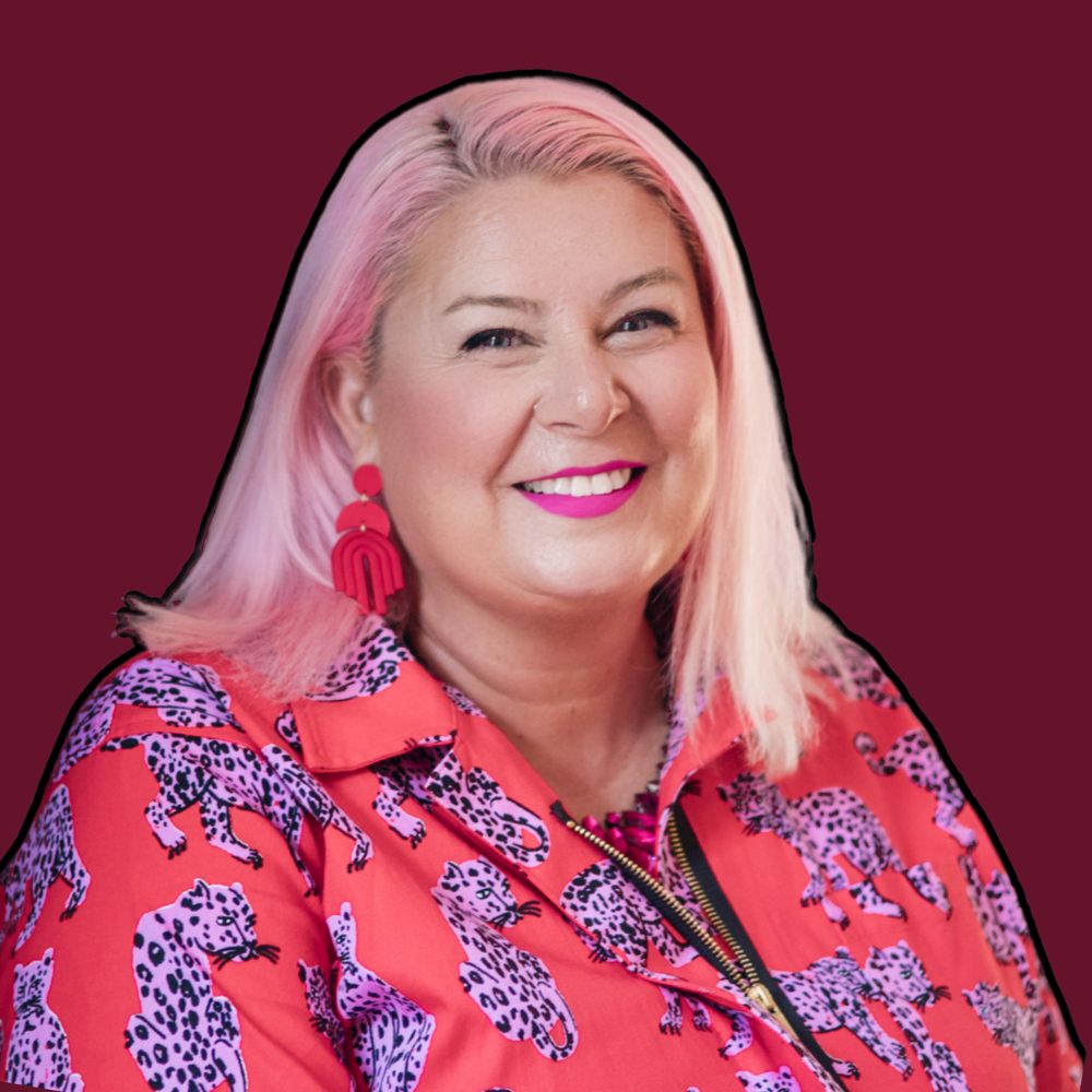 Unison Frances, smiling, with pink hair and a red leopard-print shirt.